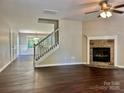 Inviting living room featuring a stone fireplace, hardwood floors, and an open staircase at 13913 Pinyon Pine Ln, Charlotte, NC 28215