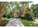 Charming brick home featuring lush landscaping, a welcoming front porch, and a circular driveway at 1638 Myers Park Dr, Charlotte, NC 28207