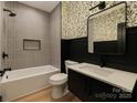 Stylish bathroom featuring gray tiled walls, black accents, and a modern vanity with a decorative leaf wallpaper accent at 415 S Boyd St, Gastonia, NC 28052