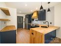 Modern kitchen boasts navy cabinets, wood countertops and accents, stainless steel appliances, and floating shelves at 415 S Boyd St, Gastonia, NC 28052