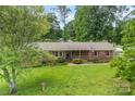 Lovely single-story brick home with a green lawn, mature trees and an American flag at 113 Helena St, Mount Holly, NC 28120