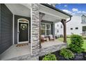 Inviting front porch showcasing stone pillars, seating, and a 'Welcome' door decor at 13222 Fiore Pl, Huntersville, NC 28078
