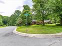 Property on a corner lot with lush landscaping, mature trees and a street sign at 2401 Wensley Dr, Charlotte, NC 28210