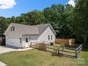 Rear of home with an attached garage, fenced-in yard, and landscaped grounds for a private outdoor space at 5764 Grassy Creek Rd, Denver, NC 28037
