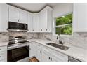 Modern kitchen with white cabinets, stainless steel appliances, granite countertops, and a window overlooking greenery at 60 Valley Nw St, Concord, NC 28025