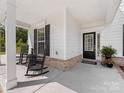 Inviting front porch with black rocking chairs, decorative plants, and a welcoming front door at 603 Southstone Dr, Matthews, NC 28104