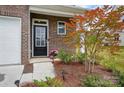 Close-up of home's front door, showcasing brick facade and landscaping with flowering plants at 6037 Chelsea Oaks Rdg # 77, Tega Cay, SC 29708