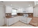 Well-lit kitchen featuring white cabinets, tile floors, updated appliances, and a stainless steel sink at 6124 Old Mt Holly Rd, Charlotte, NC 28208