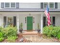Inviting front porch with a vibrant green door, American flag, and comfortable seating at 618 Heathermoor Ct, Charlotte, NC 28209