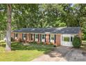Well-kept brick home boasts lush green lawn, mature trees, and a classic, timeless architecture at 844 Fieldstone Rd, Mooresville, NC 28115
