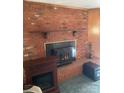 Brick fireplace featuring a rustic wood mantle and raised brick hearth, with an additional electric fireplace nearby at 8524 Anette Ave, Mint Hill, NC 28227