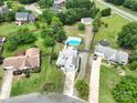 Aerial view of a home with a blue pool, wooden deck, green lawn, and mature trees, surrounded by other houses at 8540 Indian Summer Trl, Harrisburg, NC 28075