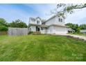 Two-story home with light siding, an attached garage, landscaped front yard, and a wooden fence, situated on a grassy lot at 8540 Indian Summer Trl, Harrisburg, NC 28075
