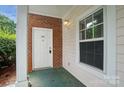Inviting covered entryway with brick accents, white door, and a bright window at 8731 Coralbell Ln, Charlotte, NC 28213