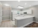 Well-lit kitchen with white cabinetry, tile floors, and a convenient breakfast bar at 8731 Coralbell Ln, Charlotte, NC 28213