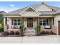 Inviting front porch with stone accents, seating, and a swing, creating a cozy curb appeal at 1115 Wynnbrook Way, Concord, NC 28027