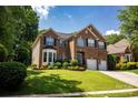 Beautiful brick home with a manicured lawn, bay window, two-car garage, and blue shutters at 12416 Kane Alexander Dr, Huntersville, NC 28078