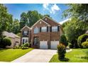 Lovely two-story brick home features a beautiful lawn, two-car garage, and lush landscaping at 12416 Kane Alexander Dr, Huntersville, NC 28078
