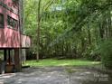 Features a raised home with a brick foundation, a lush green lawn extending into a densely wooded area at 1451 Blueberry Ln, Charlotte, NC 28226