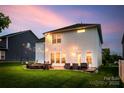 Backyard patio with string lights, a fire pit, comfortable seating, and lush green lawn, perfect for relaxation at 16008 Weeping Valley Dr, Fort Mill, SC 29715