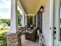 Relaxing front porch with stone pillars, wicker chairs, and inviting outdoor lighting at 3801 Creek Ridge Dr, Denver, NC 28037