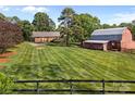 Expansive backyard features a residence and barn, with lush, striped lawns and a classic wooden fence at 425 Troutman Rd, Rockwell, NC 28138