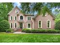 Lovely brick home with arched windows, beautiful landscaping, and well-maintained front yard at 552 Wyndham Ln, Marvin, NC 28173