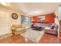 Cozy living room with wood floors, gray sofa, and a brick-red accent wall at 117 Marakery Rd # B, Mooresville, NC 28115