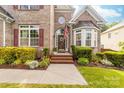 Charming brick home featuring a welcoming front entrance with a beautifully landscaped garden and a classic arched doorway at 143 Heywatchis Dr, Mooresville, NC 28115