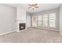 Bright living room featuring a fireplace, a ceiling fan, carpet, and natural light at 14857 Santa Lucia Dr, Charlotte, NC 28277