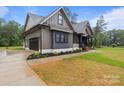 Stylish home exterior with a modern color scheme, featuring an attached garage and beautifully landscaped front yard at 153 Mills Garden Rd, Statesville, NC 28625