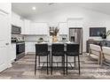Bright open-concept kitchen featuring white cabinets, stainless steel appliances, and a large island with seating at 1604 N Main St, Mount Holly, NC 28120