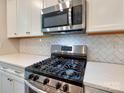Stainless steel gas range and microwave with white cabinets and backsplash at 2001 Laurel Village Cir, Belmont, NC 28012