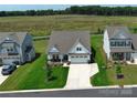 Aerial view of a well-maintained home with a lush green lawn, a two-car garage, and a neighboring field at 2048 Turnsberry Dr, Monroe, NC 28112
