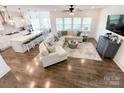 Bright, open-concept living area with hardwood floors, a comfortable sectional sofa, and modern kitchen island with seating at 2048 Turnsberry Dr, Monroe, NC 28112