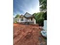 New home construction exhibits framework, brick base, and window installations amidst a spacious, ungraded lot at 208 Malvern Sw Dr, Concord, NC 28025