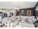 Elegant living room with a luxurious sectional, chandelier, dark accent wall, and hardwood floors at 21610 Rio Oro Dr, Cornelius, NC 28031