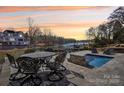 Backyard patio with wrought iron dining table, lounge chairs, and plunge pool overlooking serene waterfront and boat docks at 21610 Rio Oro Dr, Cornelius, NC 28031