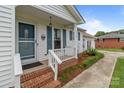 Inviting front porch with brick steps, white railings, and a charming entryway, with fresh landscaping at 2632 Montford Nw Ave, Concord, NC 28027
