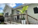 Charming side entrance with wooden porch featuring a natural wood railing, outdoor lights and plantings at 303 N Main N St, Granite Quarry, NC 28146