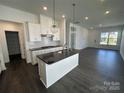 Modern kitchen with white cabinets, stainless steel appliances, a black island, and hardwood floors at 3117 Beacon Heights Rd, Indian Land, SC 29707