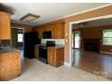 A kitchen features a black oven, black refrigerator, oak cabinets, and is adjacent to an open living area at 3240 St Vincent Dr, Claremont, NC 28610
