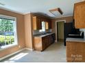 View of the kitchen showcasing oak cabinets and black appliances, adjacent to a bright, sunlit dining area at 3240 St Vincent Dr, Claremont, NC 28610