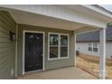 Close-up of home's entry with black front door, white trim, and light green vinyl siding at 407 Chambers St, Statesville, NC 28677