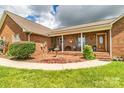 Inviting front porch with brick accents, decorative shrubbery, and comfortable seating at 4470 W Bandys Cross Rd, Claremont, NC 28610