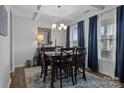 A formal dining room boasts a coffered ceiling, stylish chandelier, and dark wood furniture with elegant blue curtains at 7604 Tanglewood Way, Denver, NC 28037