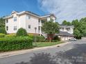 Three-story condo building with white siding, balconies and garages on a partly cloudy day at 8747 Coralbell Ln, Charlotte, NC 28213