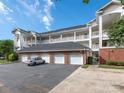 Four white garages beneath three-story condo building with balconies on a partly cloudy day at 8747 Coralbell Ln, Charlotte, NC 28213