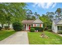 Charming one-story home featuring red accents, manicured lawn and mature trees at 1006 Washburn Ct, Monroe, NC 28110