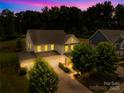 Exterior shot of a two-story home at dusk featuring a well-lit entrance and three-car garage at 10901 Greenvale Dr, Harrisburg, NC 28075